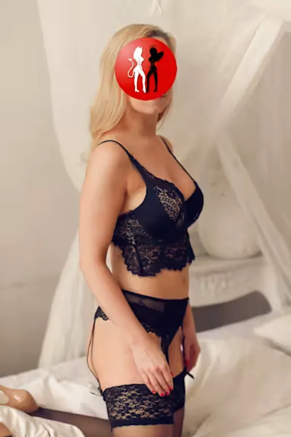 Valeska, Escort Lady in Dresden, trägt verführerische schwarze Spitzenwäsche mit Strapsen. Ihr blondes Haar fällt sanft über die Schultern, während sie elegant und doch begehrlich in die Kamera blickt. Die feine Spitze betont ihre weiblichen Kurven und lässt Raum für Fantasie. In dieser Pose verbindet Valeska stilvolle Eleganz mit der erotischen Spannung eines Moments, der nur für Eingeweihte bestimmt scheint, ein Hauch von Luxus und Lust in Dresden
